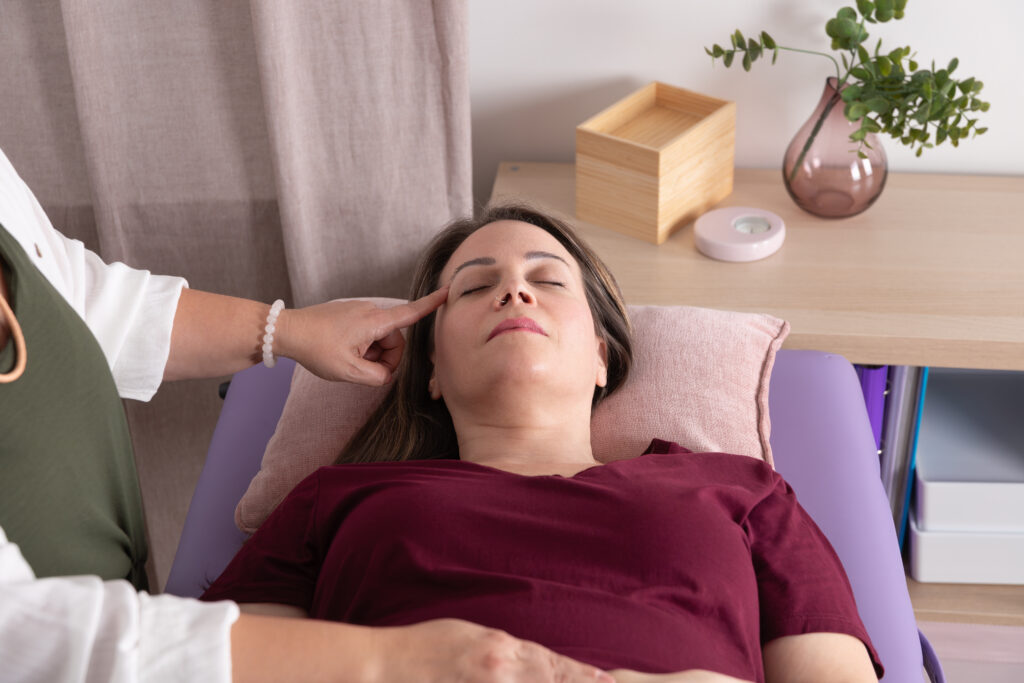 Woman on table receiving craniosacral therapy from a therapist