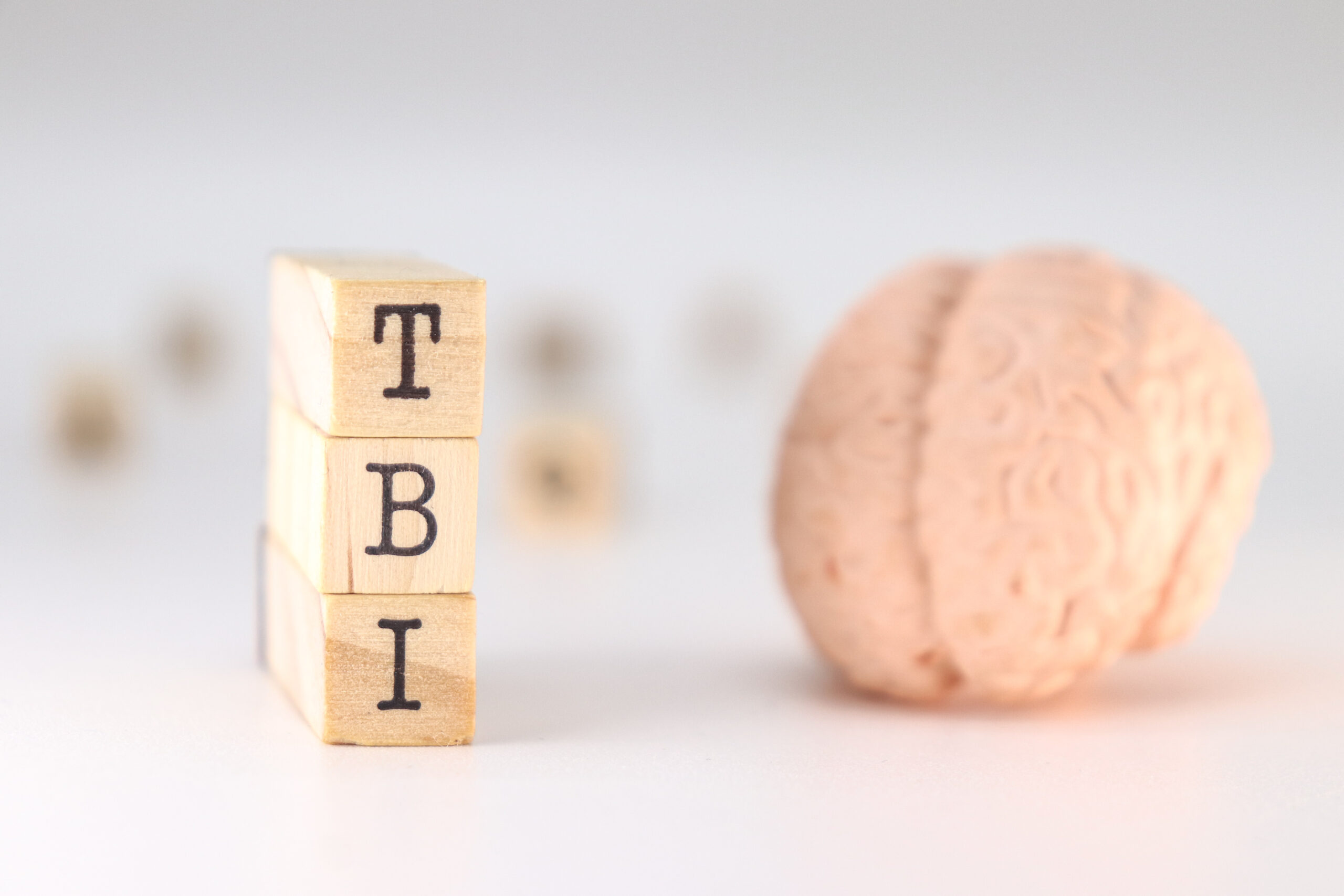 Stacked blocks spelling “TBI” next to a replica of a human brain